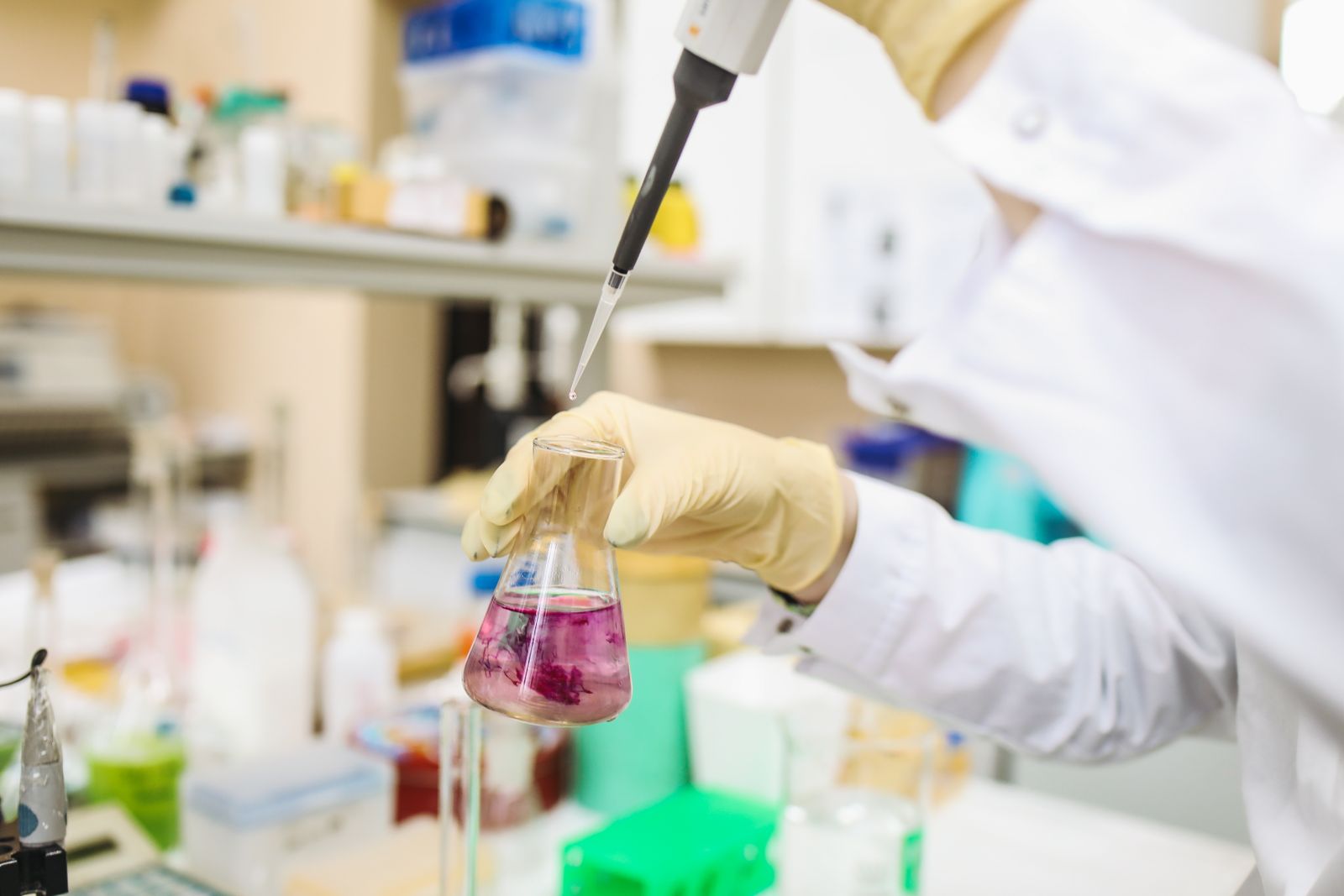 Gloved researcher using a pipette at a laboratory bench